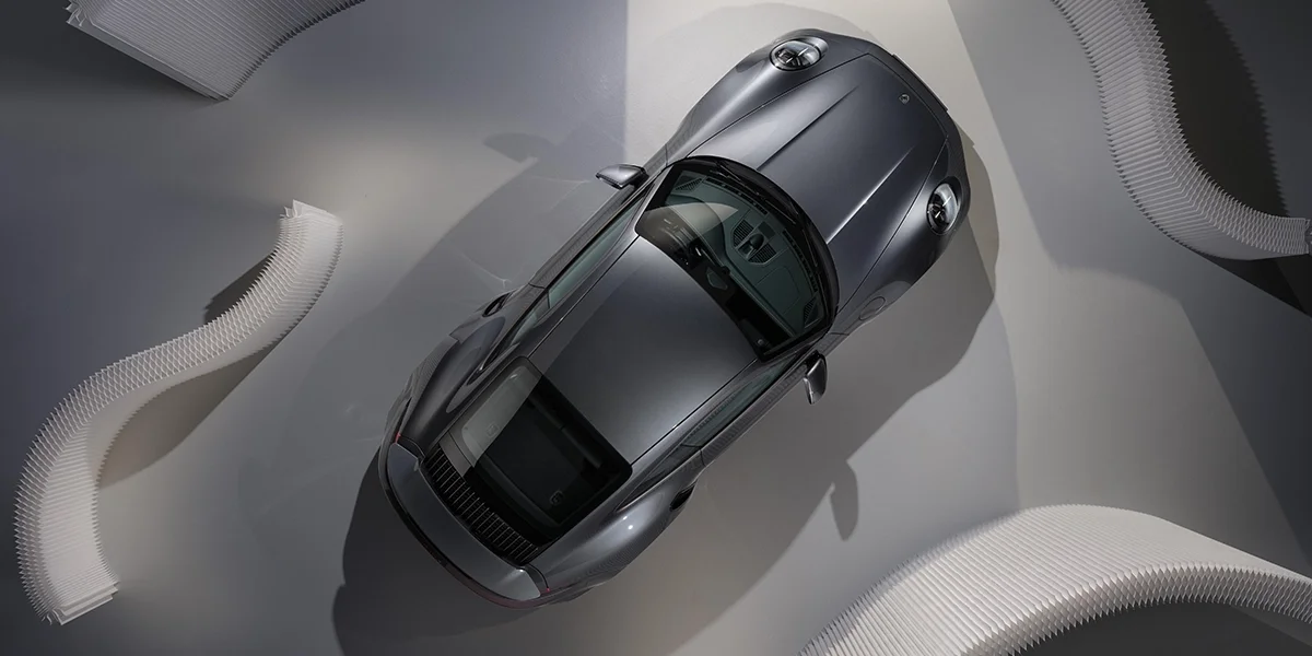 Overhead studio shot of Porsche 911 Turbo S coupe in metallic silver, highlighting aerodynamic roofline and performance styling.