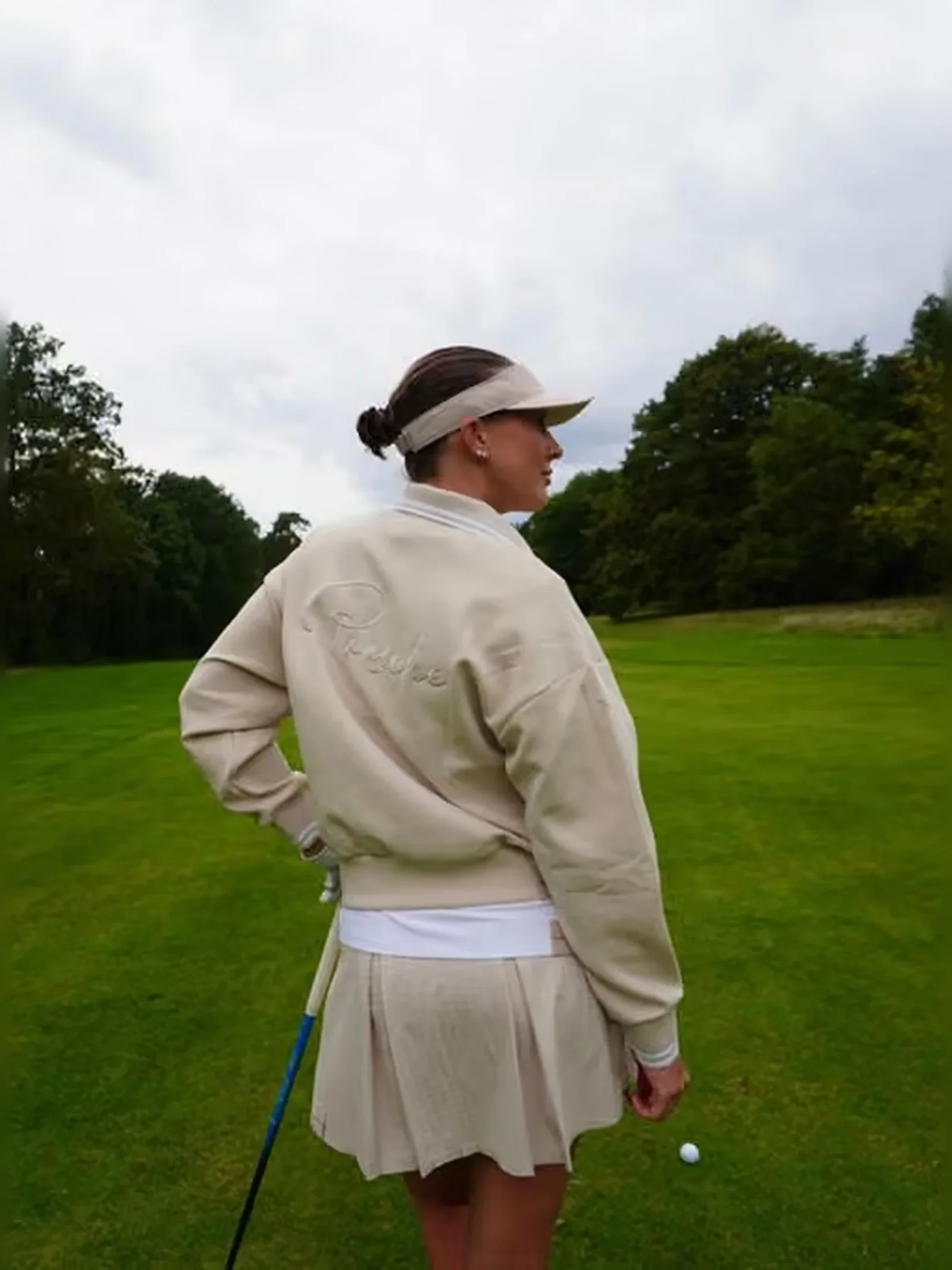 Woman wearing Porsche golf apparel on a green golf course